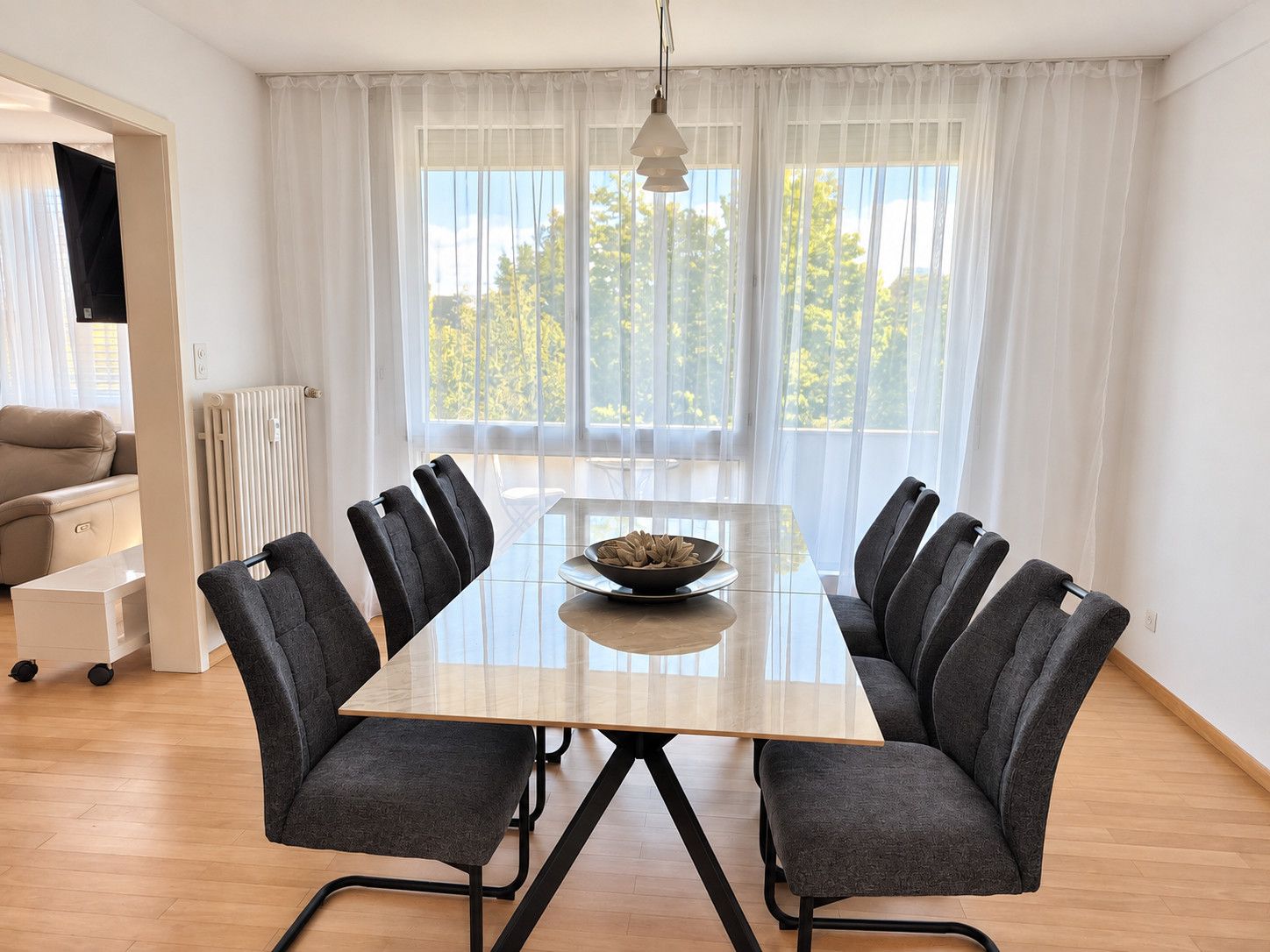 Un espace repas moderne avec une table rectangulaire, six chaises et un panier de pain.
