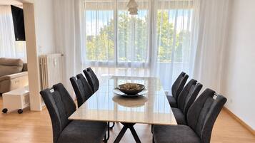 Un espace repas moderne avec une table rectangulaire, six chaises et un panier de pain.