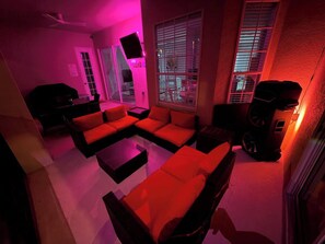 Ein Zimmer mit einer Eckcouch, einem Flachbildfernseher und einer Soundsystem-Anlage.