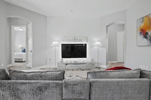A modern living room with a grey sofa set, a flat-screen TV, and a marble entertainment unit. - 5BR Pool Home Near Disney (Kissimmee)