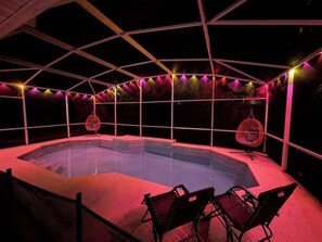 Ein Whirlpool mit umlaufender Holzterrasse, einem Hängesessel und Lichterketten.