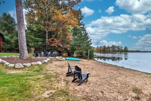 A lakeside property with a dock, outdoor seating, and a view of the lake. - Sleeps 22 Private Secluded Beach Lake Home on Eagle River Chain Of Lakes! (Eagle River)