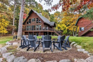 A lodge with a deck and outdoor seating area. - Sleeps 22 Private Secluded Beach Lake Home on Eagle River Chain Of Lakes! (Eagle River)