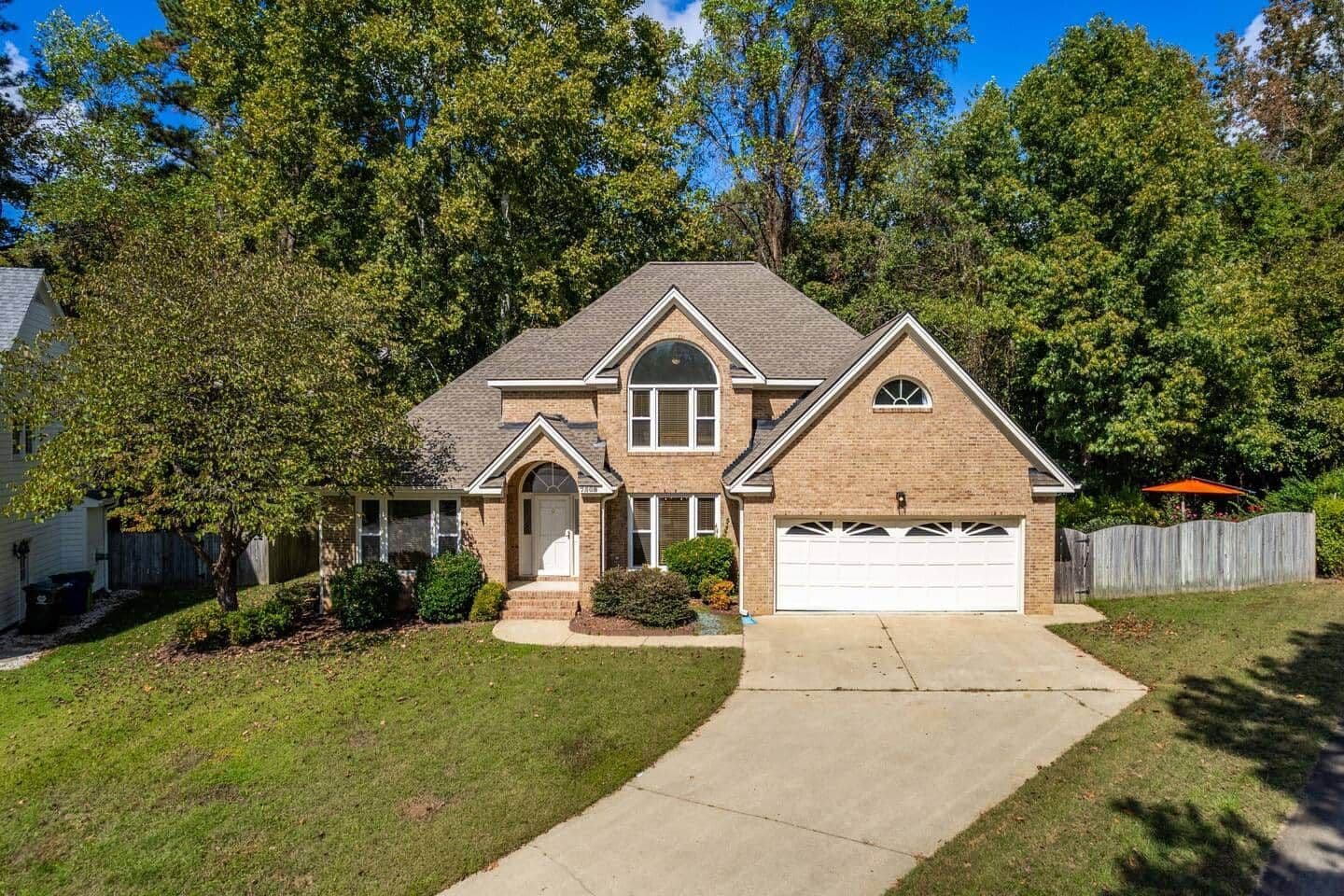 A two-story house with a garage, a front porch, and a well-maintained lawn.