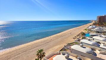 A beach resort with a pool, sun loungers, and a clear view of the ocean.