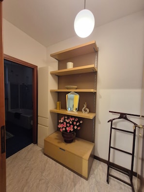 A room with a wooden cabinet, a mirror, and a vase with flowers. - Cozy apartment located right near the Rescaldina train station (Rescaldina)