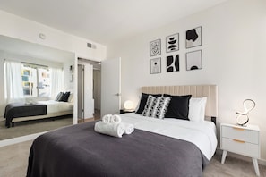 Una camera d'albergo con un letto grande, un comodino con una lampada e una parete decorata con arte astratta.