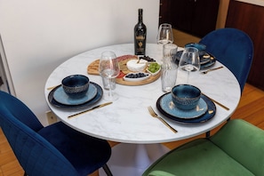 Un tavolo da pranzo rotondo con un piano in marmo bianco, circondato da sedie rivestite di blu e verde.