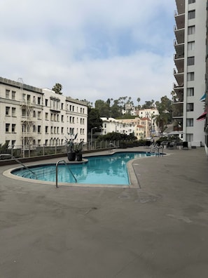 A swimming pool with a curved edge, surrounded by a concrete deck. - Hollywood Central with Pool|Free Parking|Gym (Los Angeles)