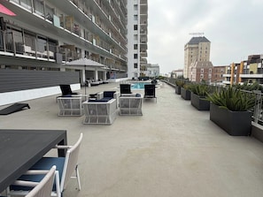 Una terrazza panoramica con posti a sedere all'aperto, una piscina e vista sugli edifici circostanti.