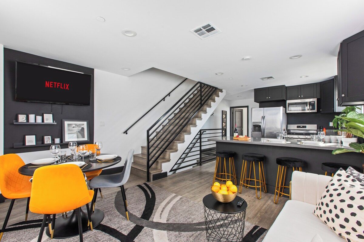 A modern kitchen with a microwave, refrigerator, and bar stools.