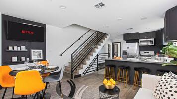 A modern kitchen with a microwave, refrigerator, and bar stools.