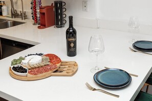 A kitchen counter with a charcuterie board, wine bottle, and plates. - Hollywood Central with Pool| Free Parking|Gym (West Hollywood)