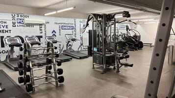 A gym with various exercise equipment, including treadmills, weight machines, and a squat rack.
