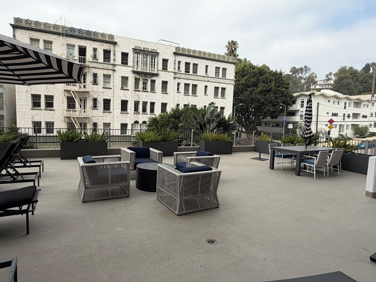 An outdoor seating area with wicker furniture and a view of a white building with multiple windows.