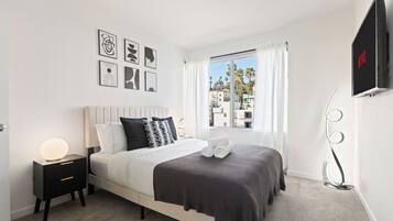 A modern bedroom with a bed, bedside table, and a TV mounted on the wall.