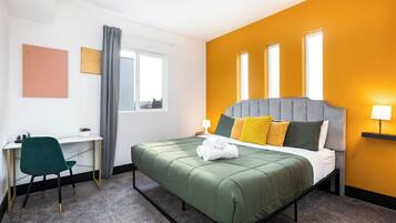 Een hotelkamer met een bed, een bureau, een stoel en een raam.