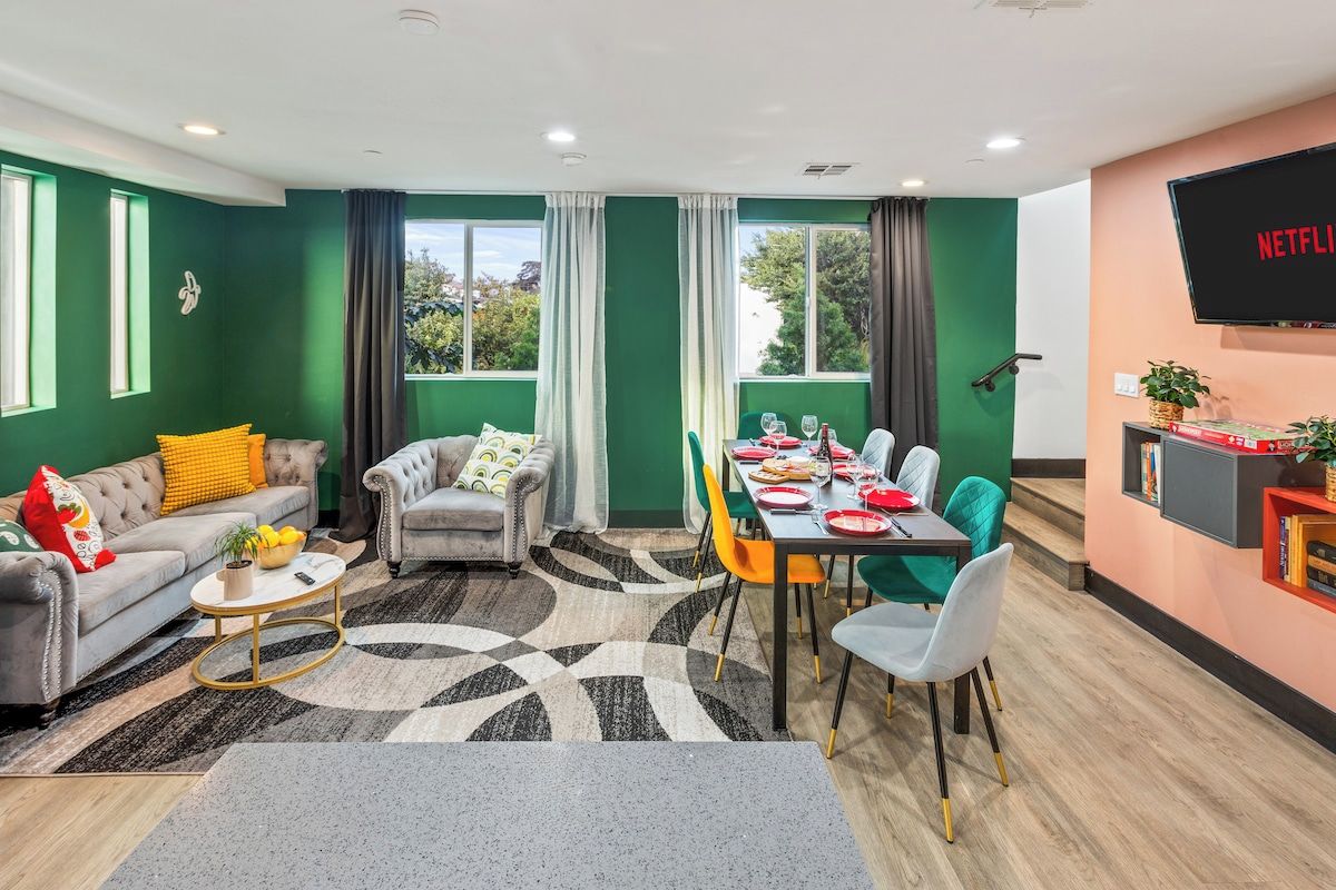 Een moderne woonkamer met een bank, fauteuil, salontafel, en een eetgedeelte met stoelen en een tafel gedekt voor een maaltijd.