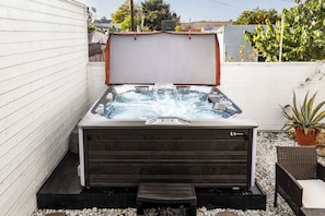Ein Whirlpool mit Holzverkleidung, einer Sitzbank und einem Blumentopf in der Nähe.