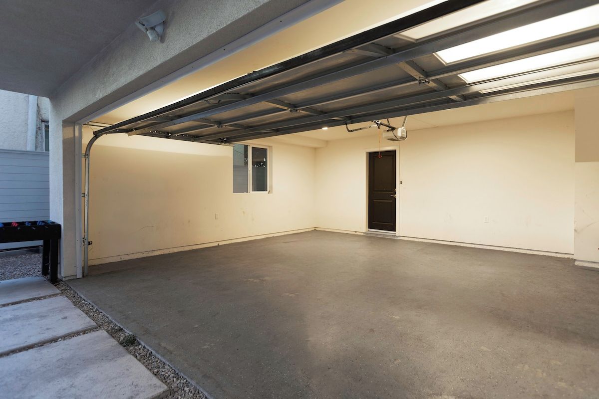 Een garage met een betonnen vloer, een metalen deur en een fluorescent armatuur.