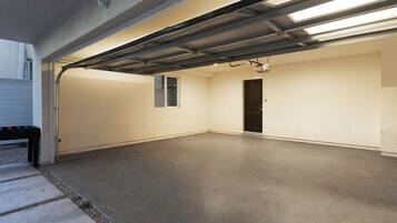 Een garage met een betonnen vloer, een metalen deur en een fluorescent armatuur.