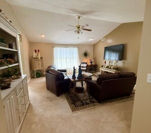 A living room with a ceiling fan, a TV mounted on the wall, and a fireplace with a mantel. - Hop Skip & Jump-Good Night Sleep (Boonville)