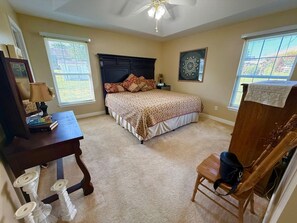Une chambre à coucher avec un lit, un bureau, une chaise et un ventilateur de plafond.