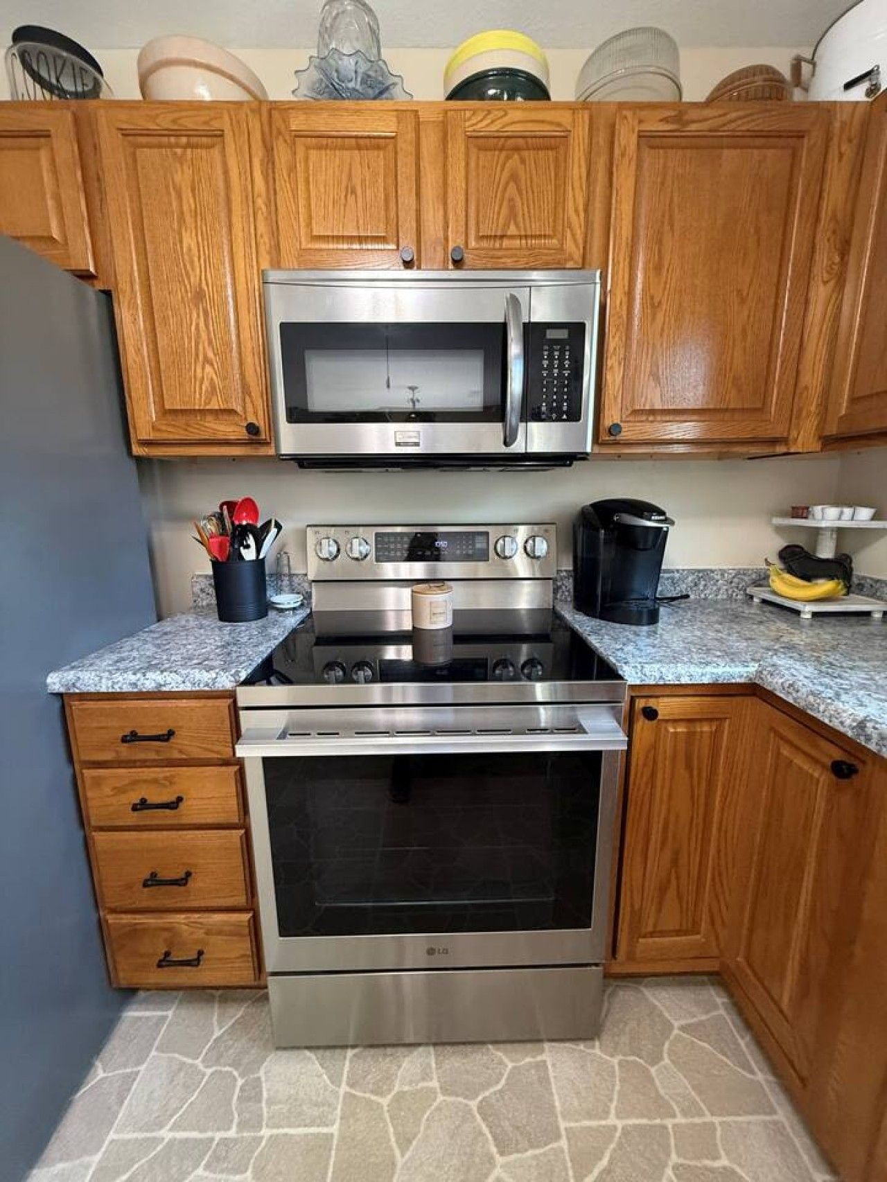 A kitchen with wooden cabinets, a microwave, an oven, and a granite countertop.