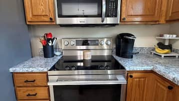 A kitchen with wooden cabinets, a microwave, an oven, and a granite countertop.