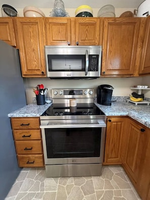 A kitchen with wooden cabinets, a microwave, an oven, and a granite countertop. - Hop Skip & Jump-Good Night Sleep (Boonville)