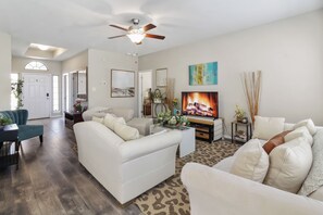A spacious living room with a fireplace, white sofas, and a television. - Furnished 3BR Home Near Baylor Scott & White, Monthly Stays (Temple)