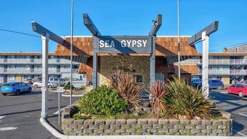 L'ingresso di un hotel con un cartello che riporta 'SEA GYPSY', una facciata in pietra e un parcheggio con auto.