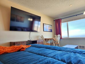 A bedroom with a bed, a desk, a chair, a television, and a window with curtains. - Oceanfront Condo With Kitchen, Pool, Hot Tub (Lincoln City)