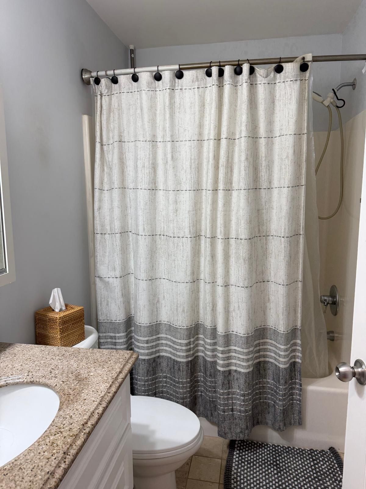 A bathroom with a shower curtain, a toilet, and a sink.