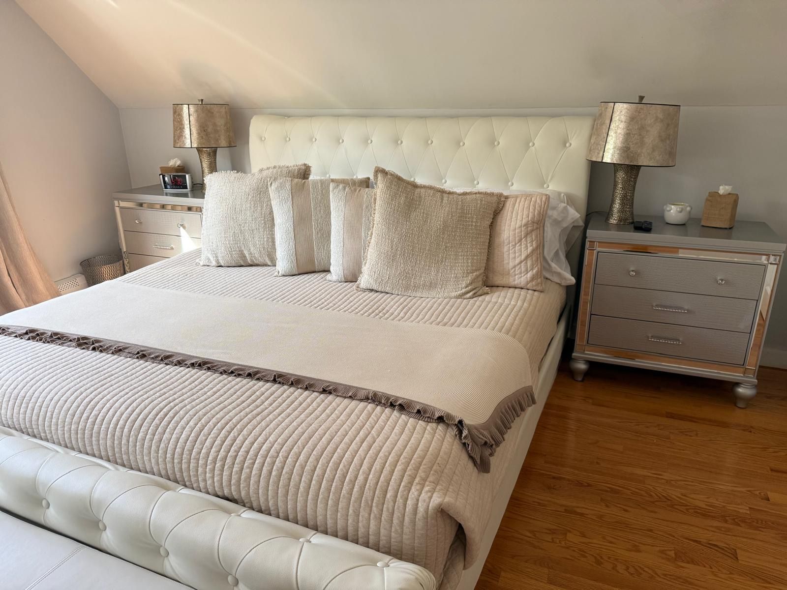 A bedroom with a large bed, two bedside tables, a nightstand, and a lamp.