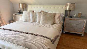 A bedroom with a large bed, two bedside tables, a nightstand, and a lamp.