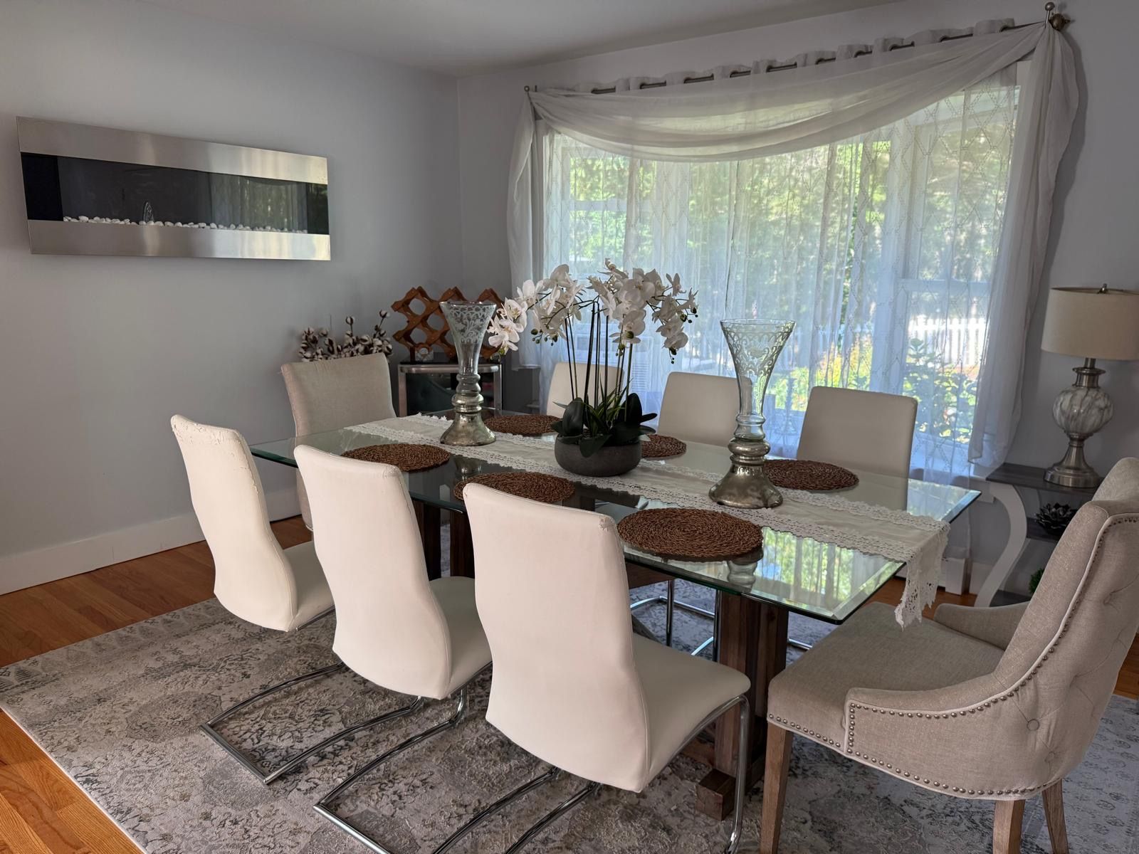 A dining area with a glass table, white chairs, and a decorative centerpiece.