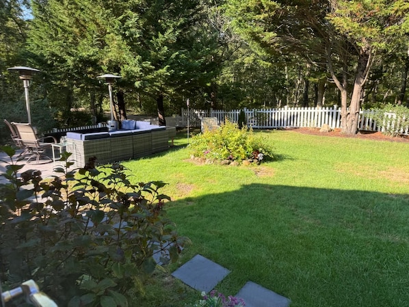 A backyard with a seating area, a white fence, and a variety of plants.