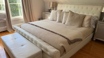 Une chambre à coucher avec un grand lit, une table de chevet, une lampe et une fenêtre avec des rideaux.