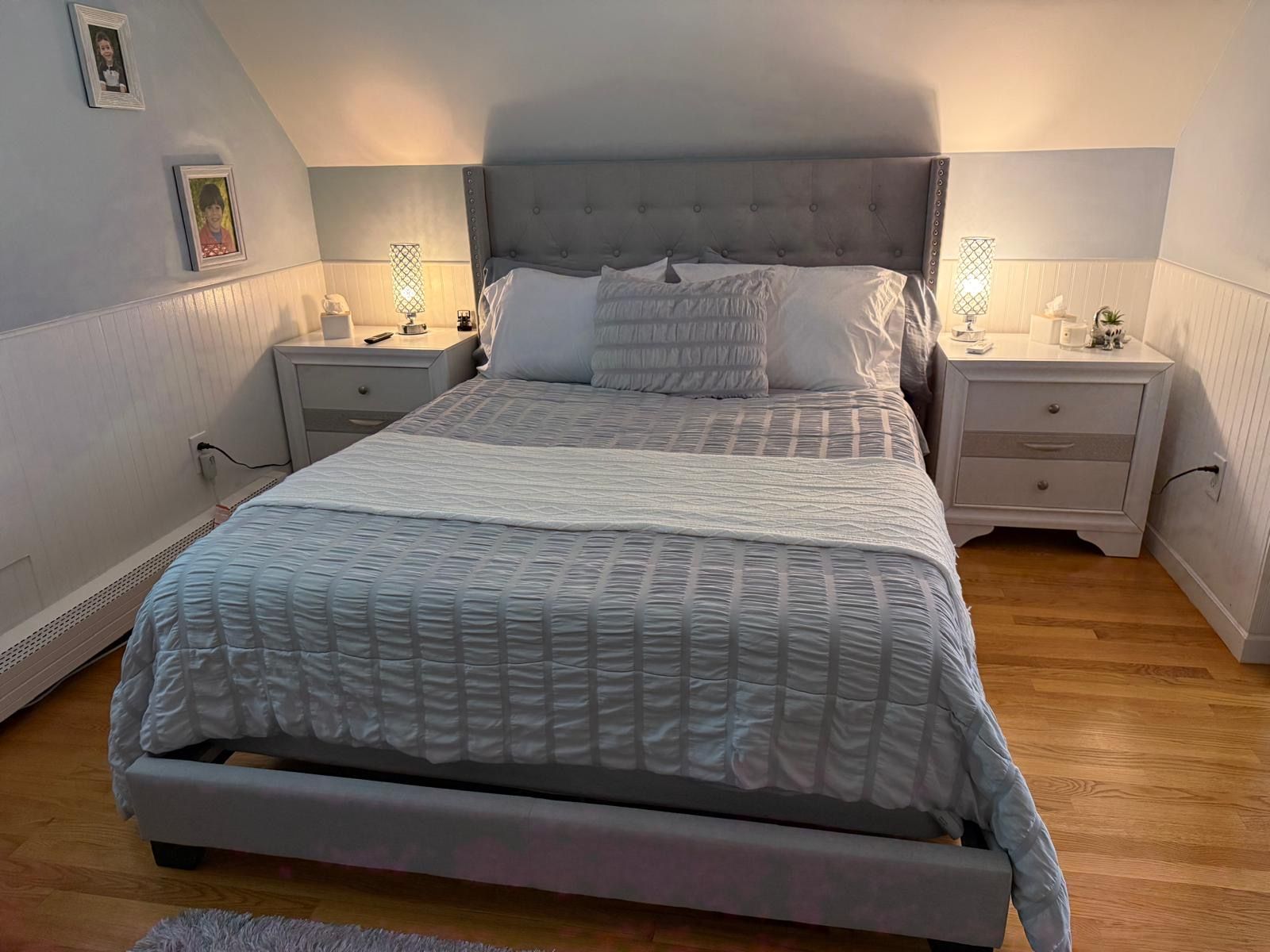 A bedroom with a large bed, two bedside tables, and a nightstand with a lamp.