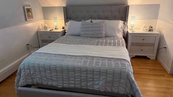A bedroom with a large bed, two bedside tables, and a nightstand with a lamp.