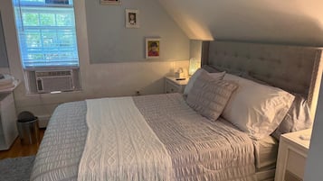 Un dormitorio con una cama, una mesita de noche, una lámpara y una ventana con persianas.