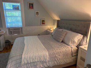 Un dormitorio con una cama, una mesita de noche, una lámpara y una ventana con persianas.