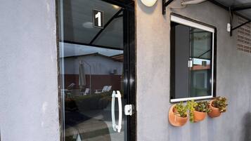 A building entrance with a glass door, a number '1' sign, a potted plant, and a doormat.