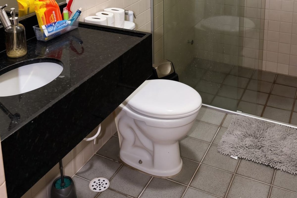 A bathroom with a black sink, white toilet, and a glass shower enclosure.