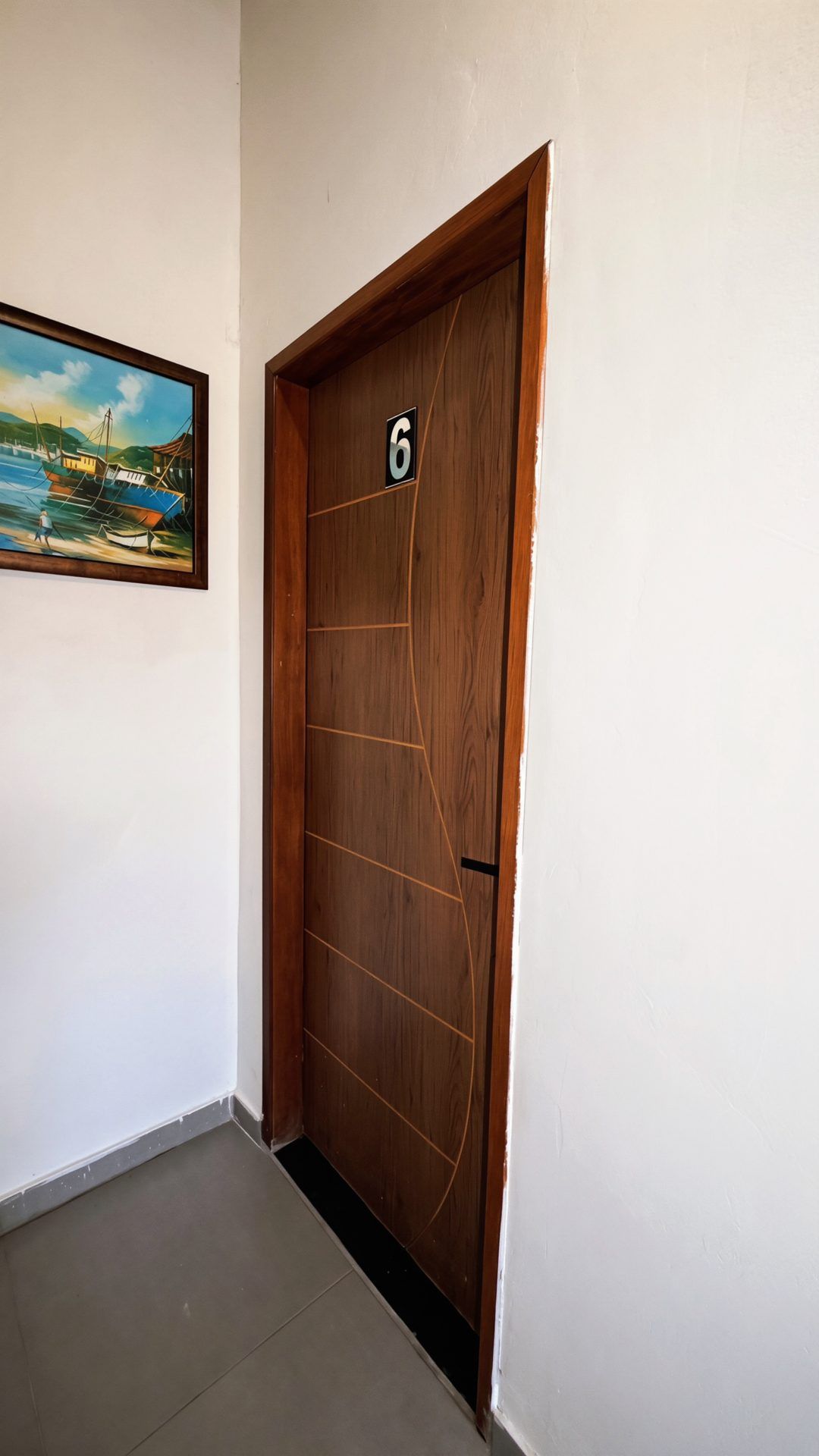Eine Holztür mit der Nummer 6, ein Bild eines Bootes an der Wand und ein gefliester Boden.