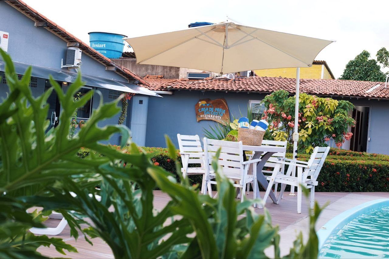Zona junto a la piscina con mesa y sillas, un depósito de agua y un edificio con un letrero.
