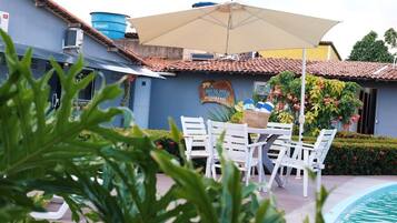 Zona junto a la piscina con mesa y sillas, un depósito de agua y un edificio con un letrero.