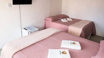 A hotel room with two beds, a flat-screen TV, a bedside table, and a ceiling light.