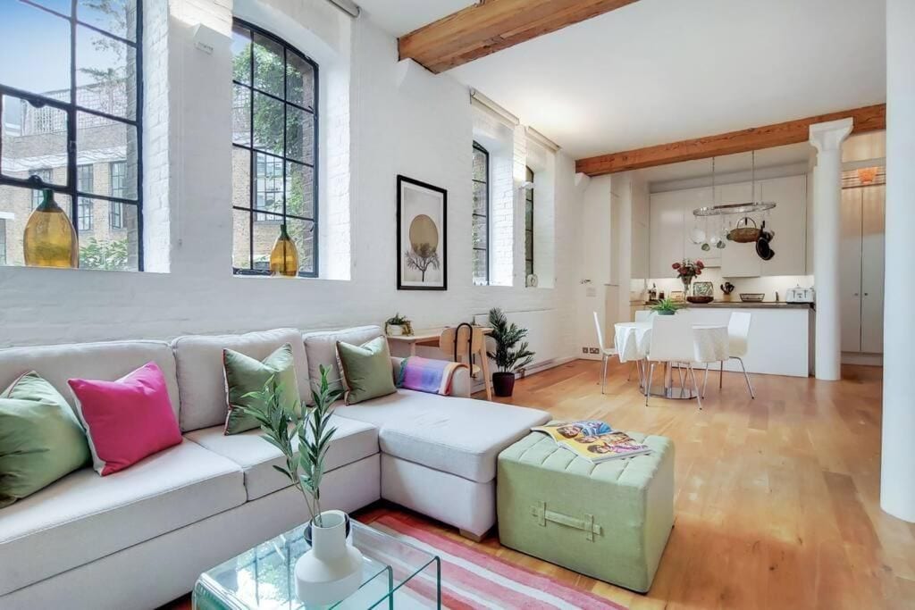 A modern living room with a sectional sofa, a glass coffee table, and a dining area with a white table and chairs.